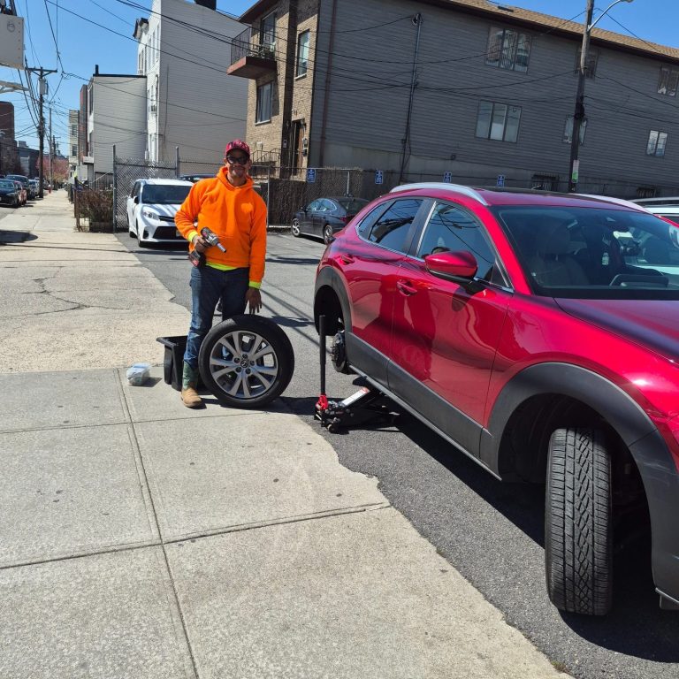Flat Tire Change & Roadside Assistance in Hoboken NJ | Happy Road Services Happy Road Services technician changing a flat tire for a driver in Hoboken NJ — 24/7 roadside tire service